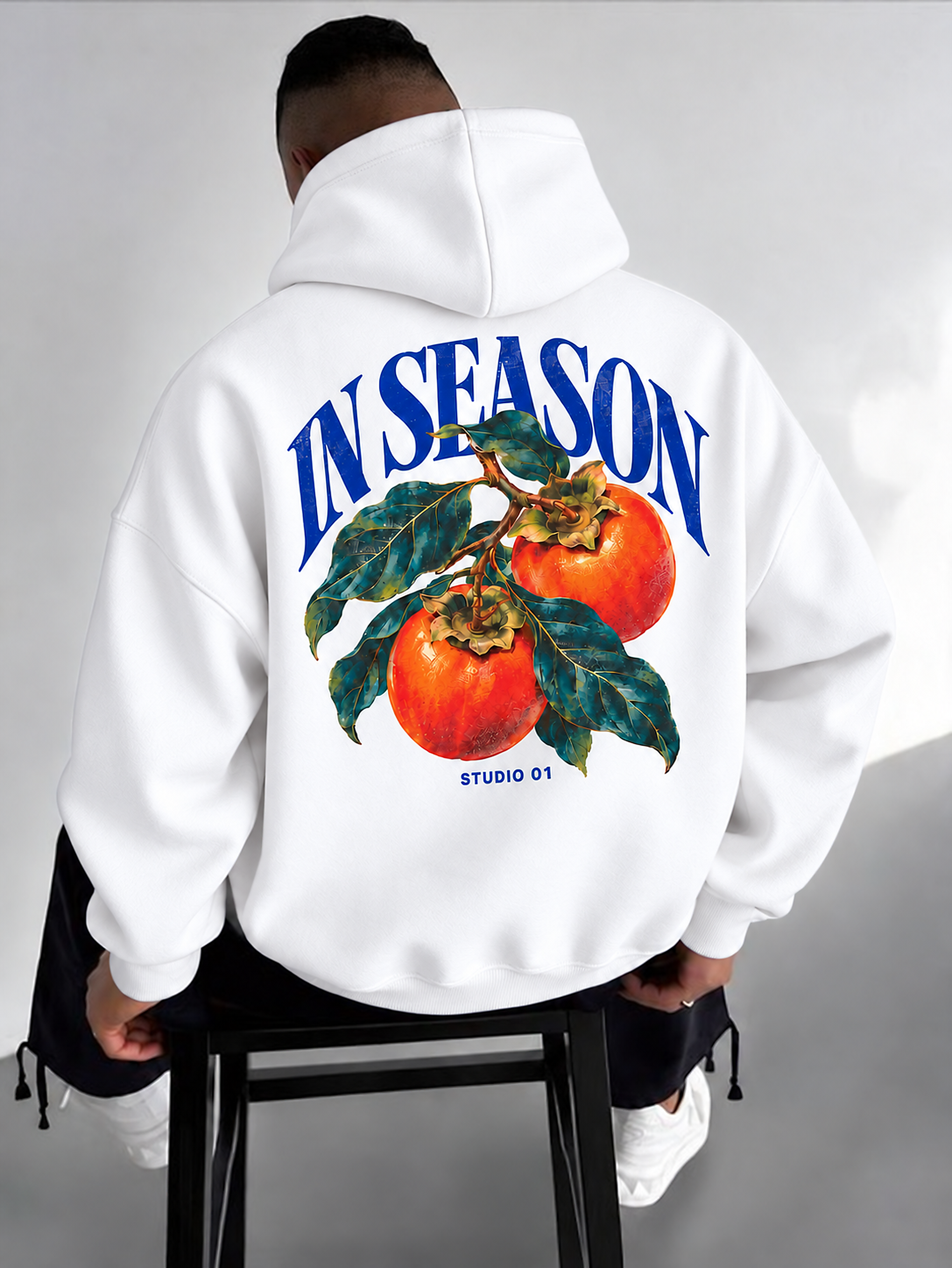Model wearing a white In Season hoodie with persimmon artwork